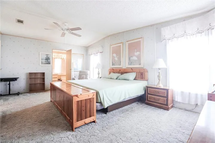 Carpeted bedroom with multiple windows, lofted ceiling, and a textured ceiling