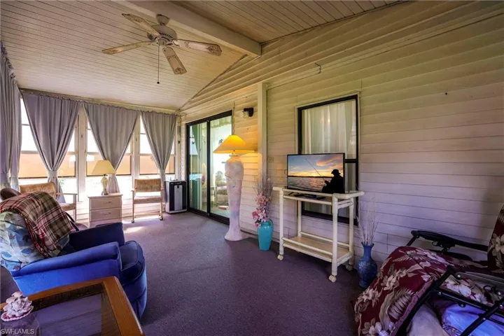 Sunroom / solarium featuring vaulted ceiling with beams, wood ceiling, and ceiling fan