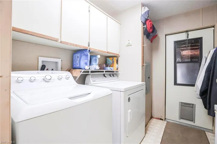 Laundry room featuring cabinets, separate washer and dryer, electric panel, and a textured ceiling