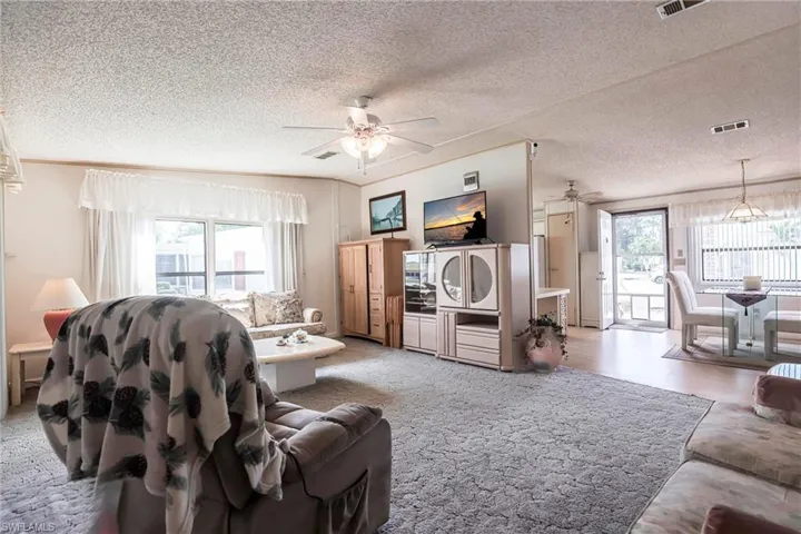 Living room featuring ceiling fan, a textured ceiling, and a wealth of natural light
