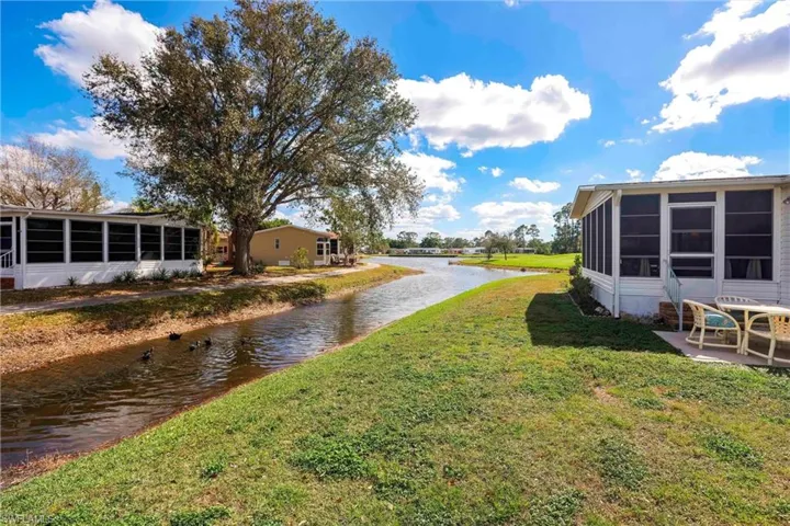 View of yard with a patio, a water view, and a sunroom