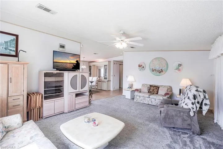 Carpeted living room with ceiling fan and a textured ceiling