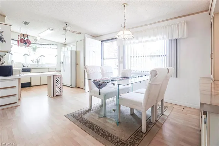 Dining room with ceiling fan, light hardwood / wood-style flooring, and a textured ceiling