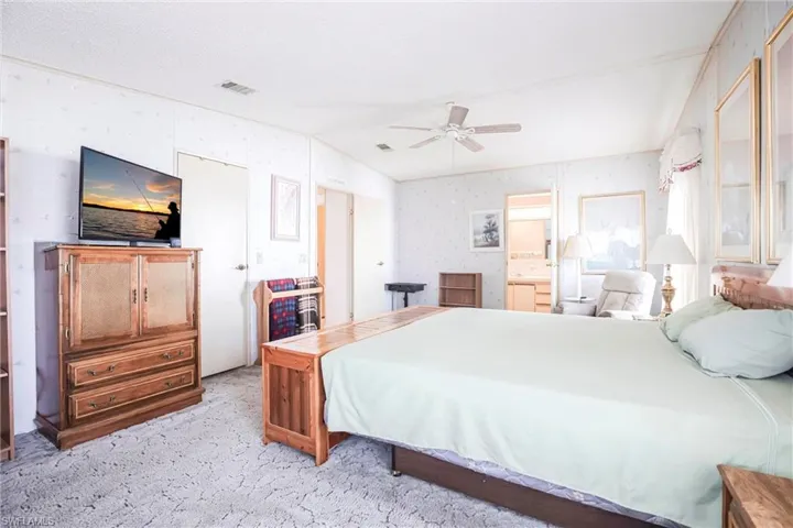 Bedroom with lofted ceiling, light colored carpet, connected bathroom, and ceiling fan