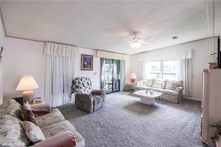 Carpeted living room featuring a textured ceiling and ceiling fan