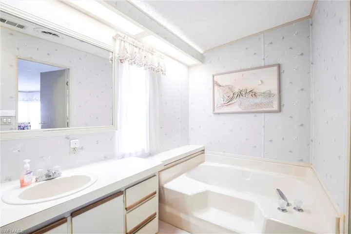 Bathroom featuring vanity, a textured ceiling, and a bathtub