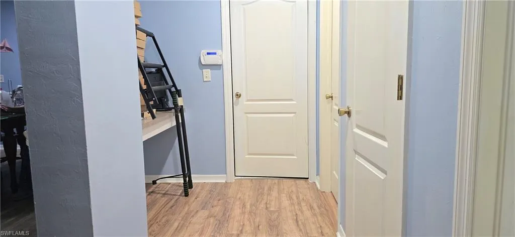 Hallway featuring light wood-type flooring and baseboards