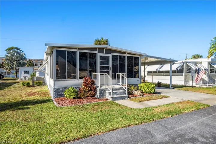 View of front of house with an attached carport, a sunroom, and driveway