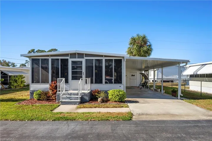 Manufactured / mobile home with a sunroom, driveway, a front yard, and an attached carport