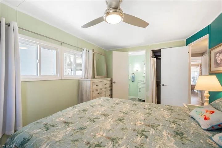 Bedroom with a ceiling fan, connected bathroom, and ornamental molding