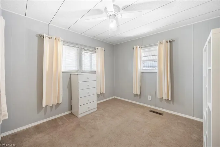 Unfurnished bedroom featuring carpet, a ceiling fan, and wood walls