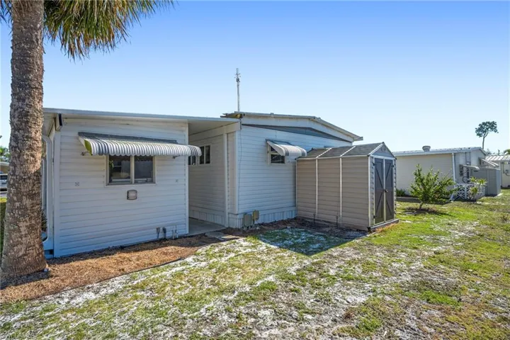 Rear view of property featuring a shed and a yard