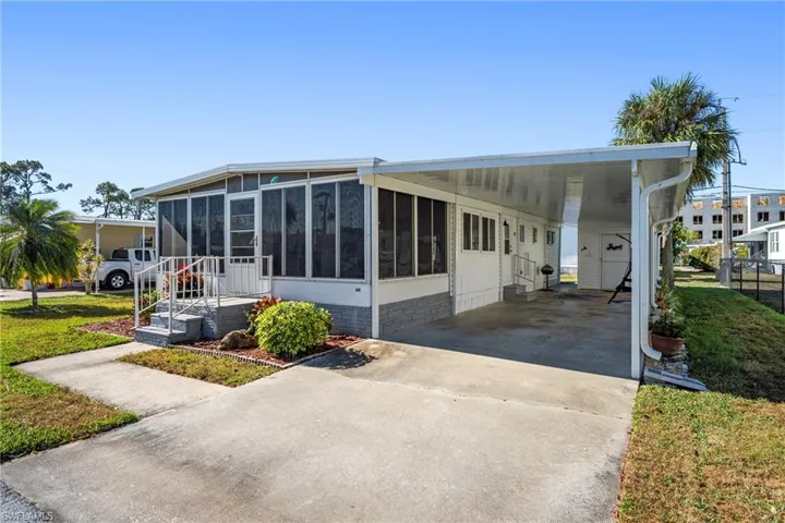 View of front facade featuring concrete driveway, a front lawn, an attached carport, and a sunroom