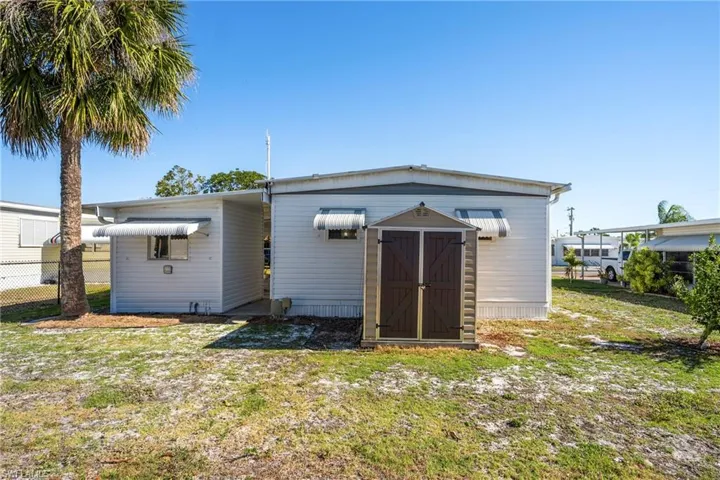 Back of house with a storage unit