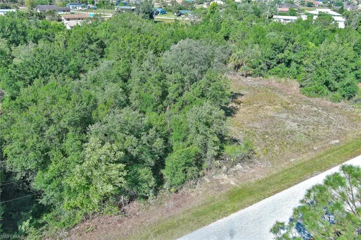 Aerial view of property and surrounding area with a heavily wooded area