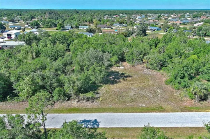 Aerial view of property and surrounding area with a heavily wooded area