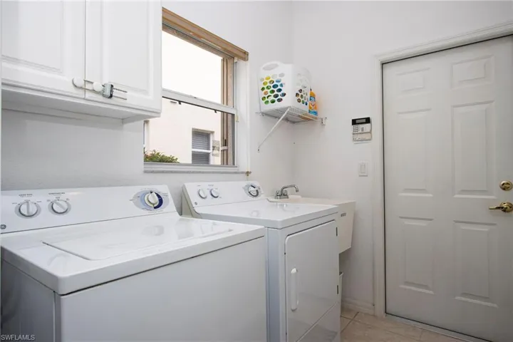 Laundry area featuring cabinets, light tile patterned floors, and washing machine and dryer