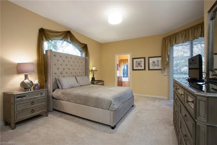 Bedroom with light colored carpet and connected bathroom