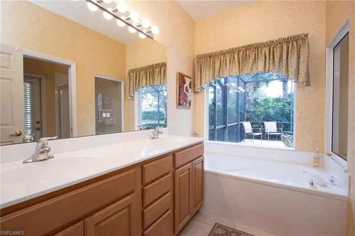 Bathroom with a washtub, tile patterned floors, vanity, and a healthy amount of sunlight