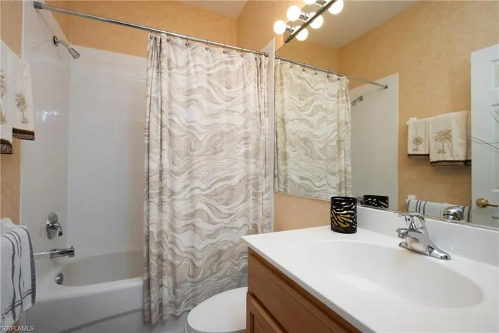 Full bathroom with toilet, vanity, and shower / bathtub combination with curtain