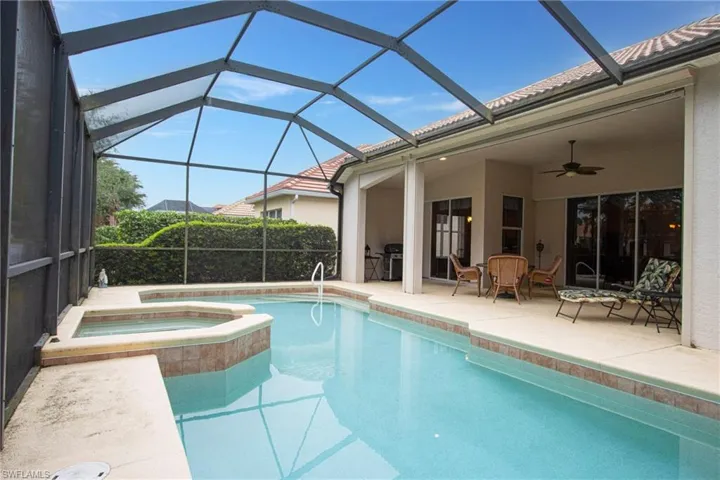 View of swimming pool featuring ceiling fan, an in ground hot tub, a lanai, a grill, and a patio area