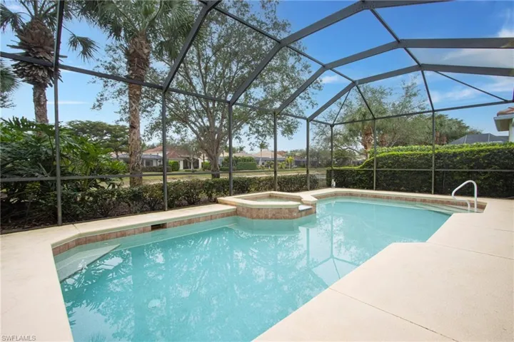 View of swimming pool with glass enclosure, an in ground hot tub, and a patio area