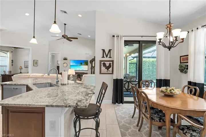 Kitchen featuring a sink, lofted ceiling, ceiling fan, open floor plan, and a center island with sink