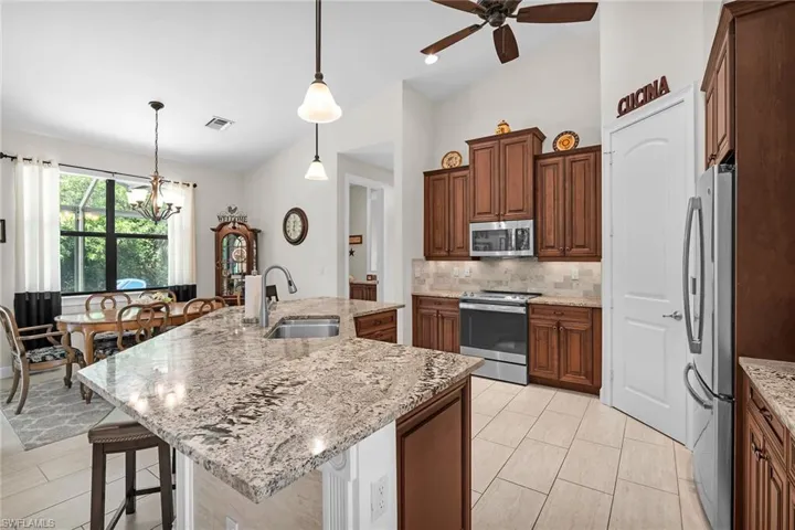 Kitchen with stainless steel appliances, a sink, a chandelier, backsplash, and a kitchen bar