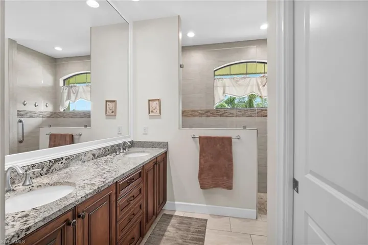 Full bath featuring walk in shower, double vanity, tile patterned floors, and recessed lighting