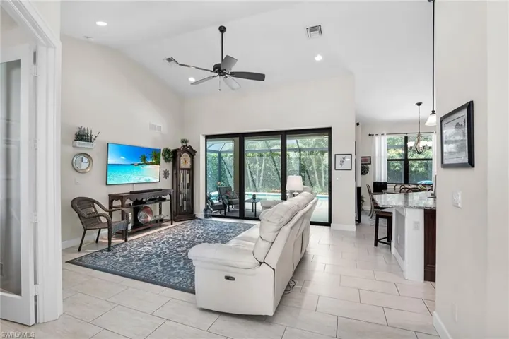 Living area with a ceiling fan, lofted ceiling, recessed lighting, and baseboards