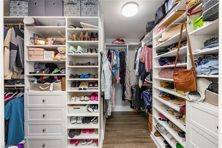 Walk in closet with dark wood-style floors
