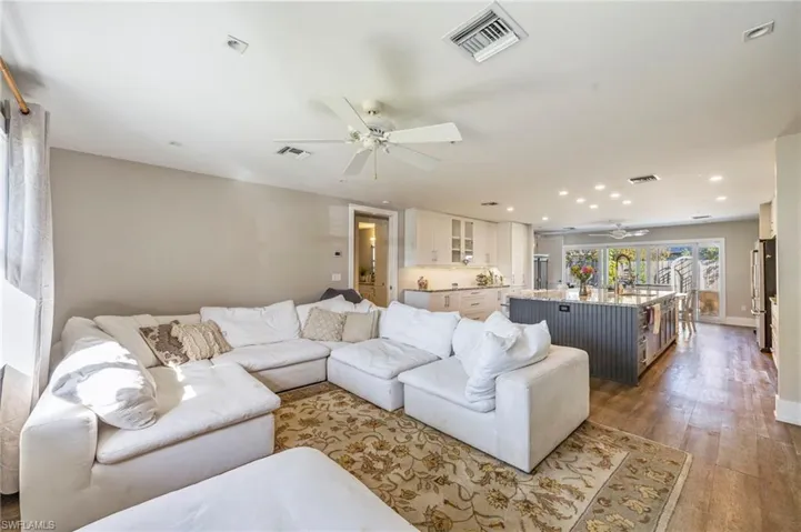 Living room with light wood-style floors, ceiling fan, and recessed lighting
