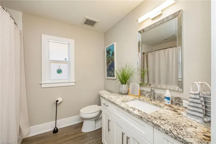 Full bath featuring vanity, curtained shower, and dark wood finished floors