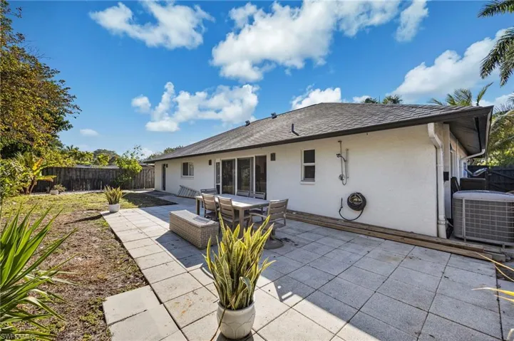 Rear view of property with stucco siding, a patio, a fenced backyard, roof with shingles, and outdoor dining area