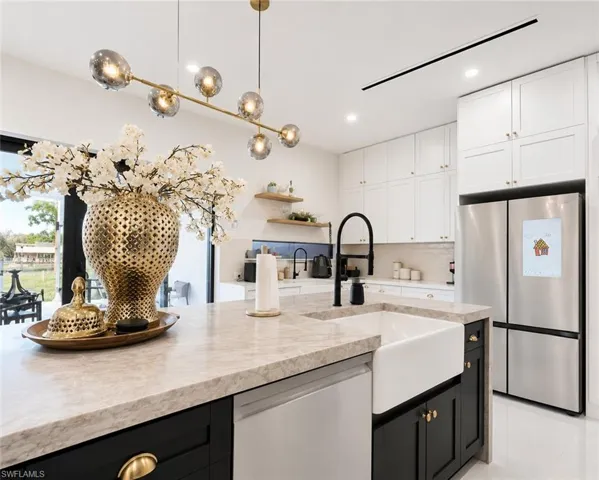 Gourmet kitchen featuring a large island with an apron-front sink, stone countertops, black cabinetry, and a modern chandelier