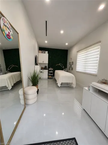 Spacious interior featuring light gray polished tile flooring, recessed ceiling lighting, and a textured green accent wall
