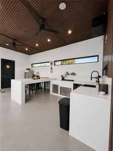 Contemporary kitchen featuring a slatted wood-finish ceiling, integrated recessed lighting, and modern ceiling fans