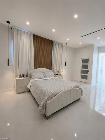 Bedroom featuring a vertical wood-slat accent wall, recessed lighting, and light-toned tile flooring