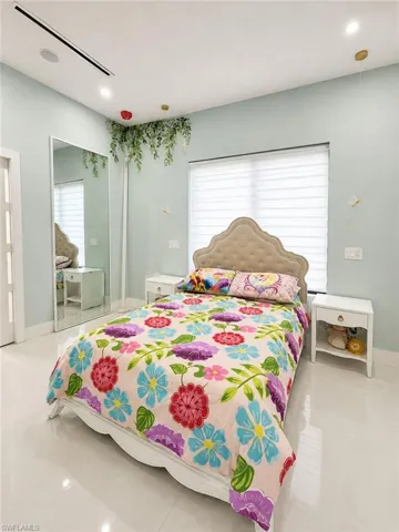 Bedroom featuring a full-height mirror, light-toned tile flooring, and integrated ceiling lighting
