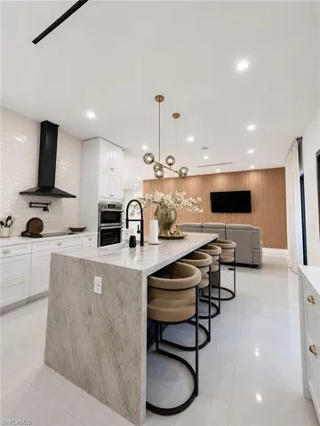 Modern kitchen island featuring a waterfall edge, integrated sink, and an elegant pendant light fixture