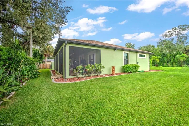 Rear view of property featuring a lawn and a sunroom