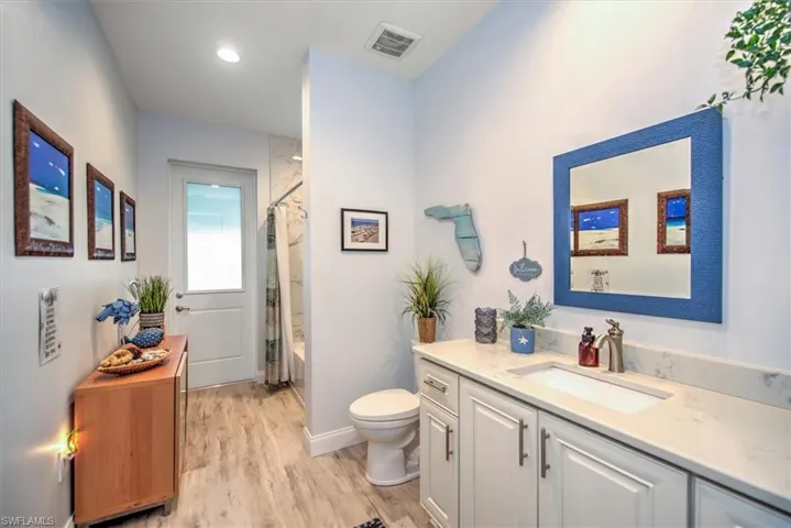 Full bathroom with vanity, toilet, hardwood / wood-style flooring, and shower / bath combo