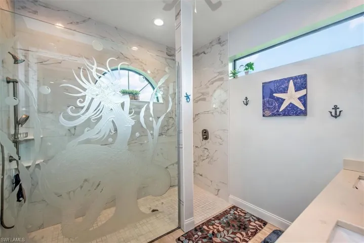 Bathroom featuring a shower with shower door and plenty of natural light