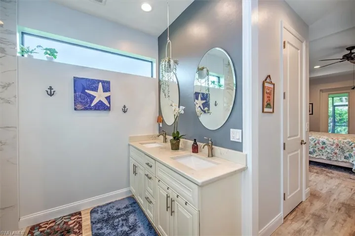 Bathroom with double sink vanity, hardwood / wood-style floors, and ceiling fan