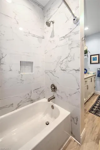 Bathroom featuring vanity, hardwood / wood-style floors, and tiled shower / bath