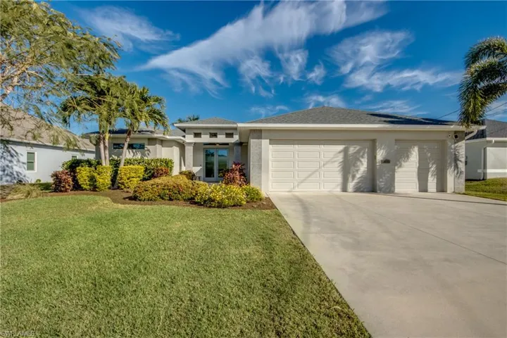 View of front of property featuring a front yard, stucco siding, and driveway