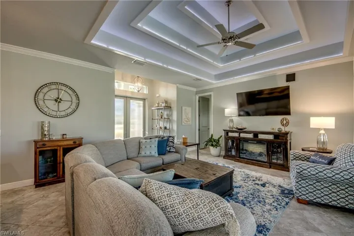 Living room with a ceiling fan, ornamental molding, and a raised ceiling