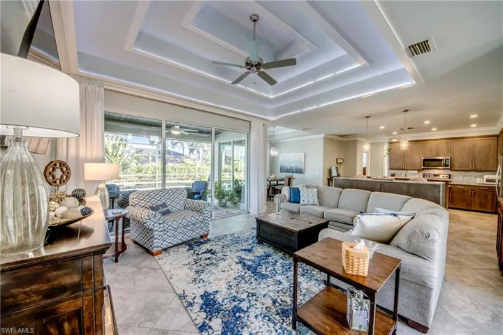 Living area with a sunroom, ceiling fan, crown molding, recessed lighting, and a tray ceiling
