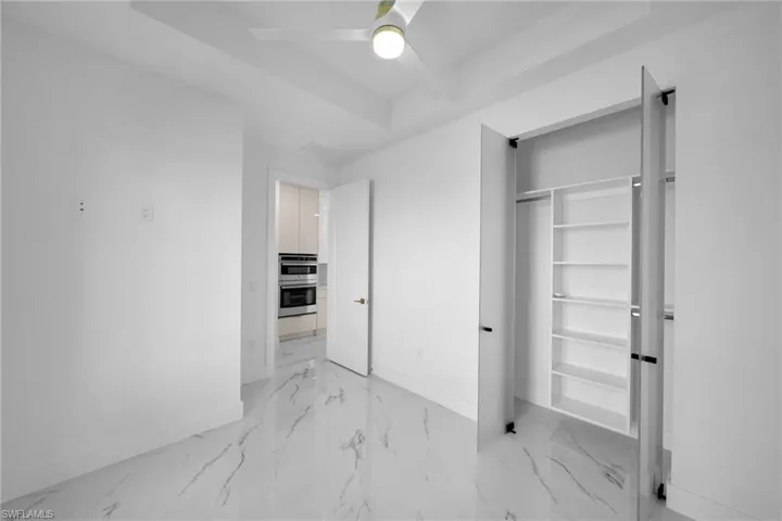 Unfurnished bedroom with a closet, ceiling fan, and light tile floors