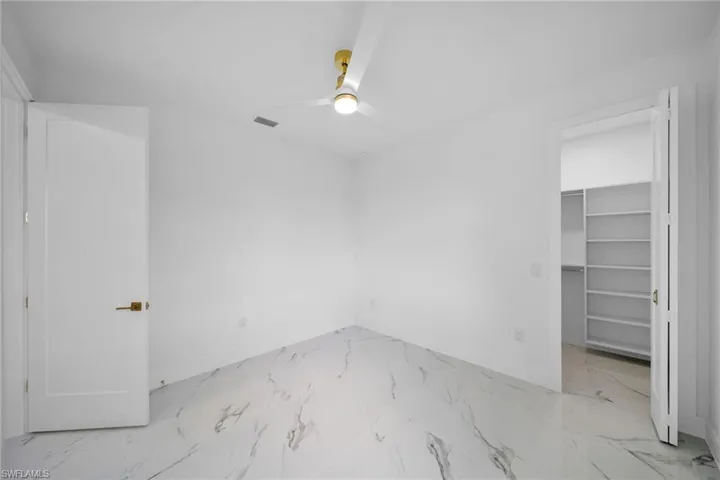 Unfurnished bedroom with ceiling fan, a closet, a walk in closet, and light tile floors
